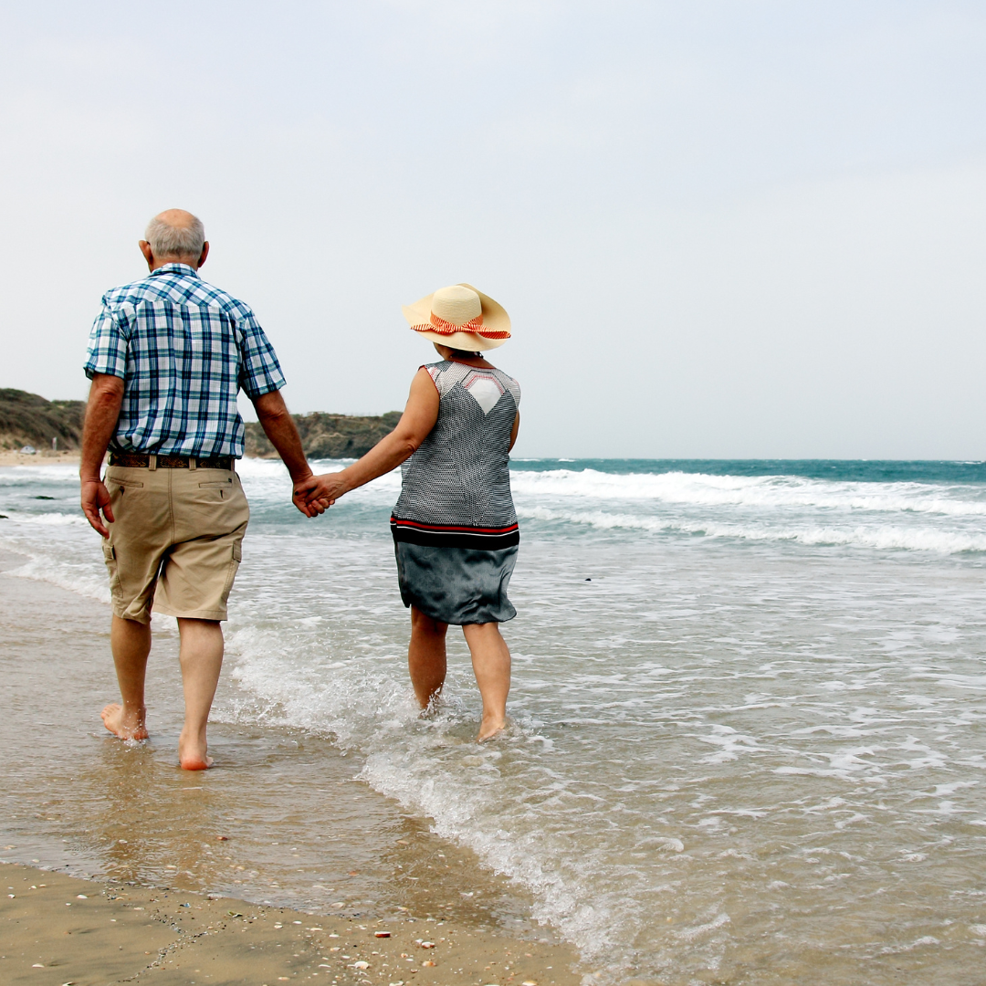 Elderly couple walking on the beach in the ocean